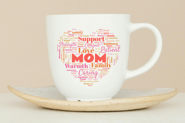 A mug on a saucer, with a word cloud about Mom in the shape of a heart printed on the mug